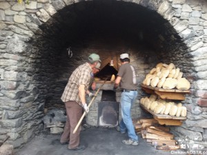 Forno del vilaggio w Buthier i piekarze w akcji podczas wyciągania ciepłego chleba.